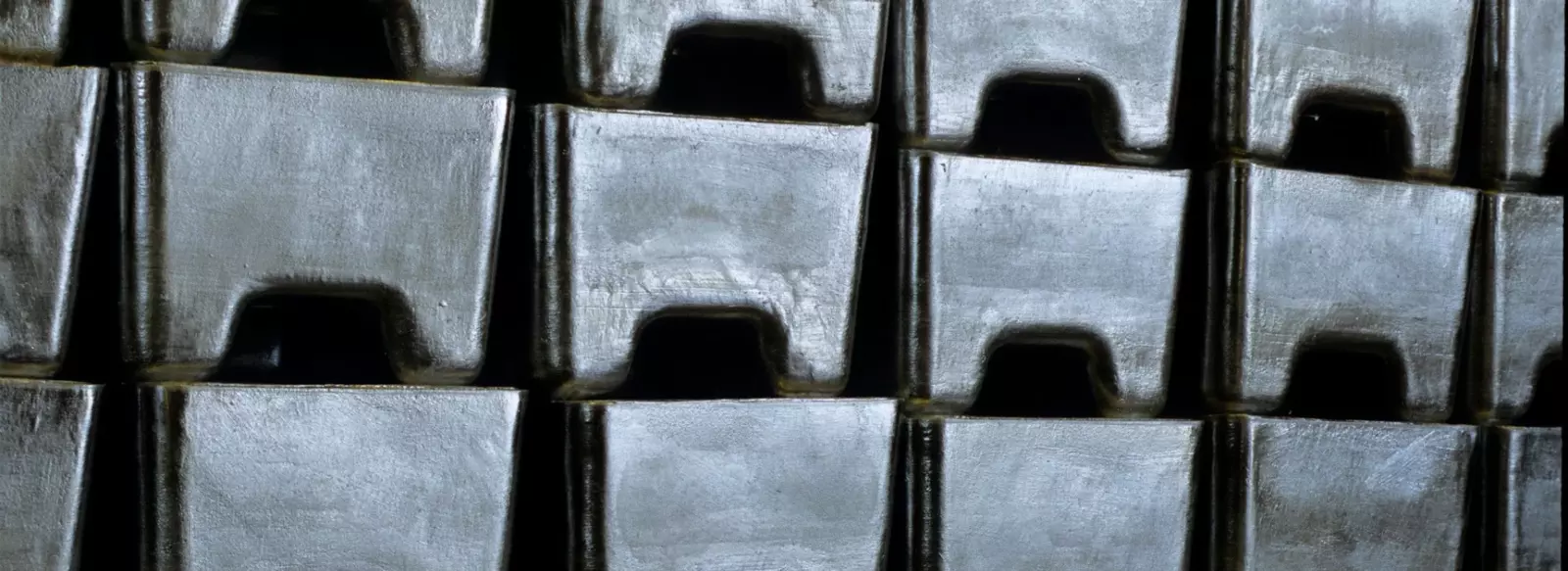 Stacked metal ingots arranged in a storage facility.
