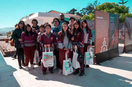 Group of students and adults posing outdoors with bags and educational displays in the background.