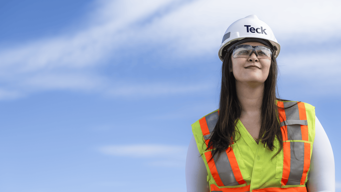 Person in safety gear and helmet looks up at the sky with a thoughtful expression.